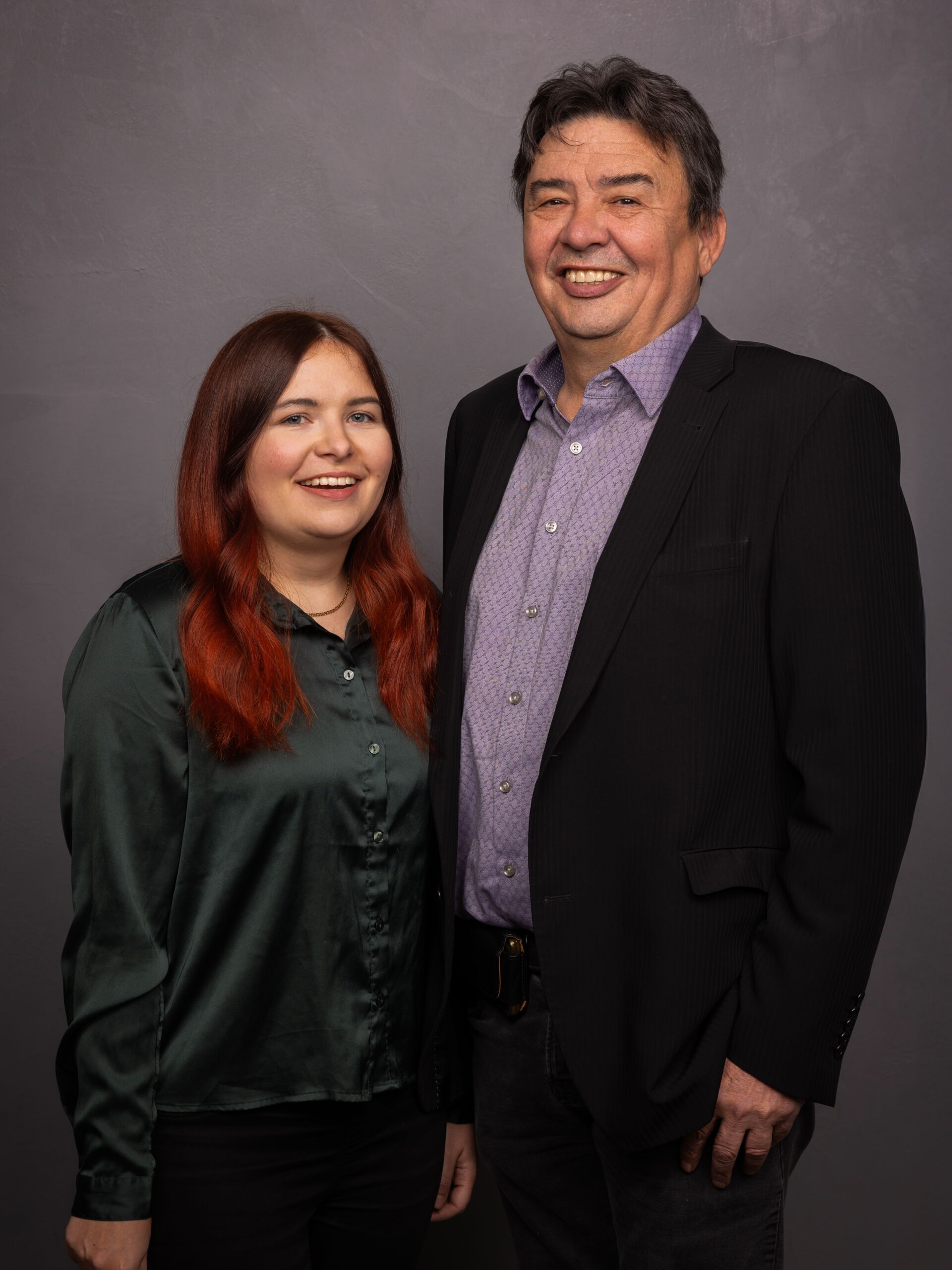  Sara und Jan nebeneinander vor neutralem Hintergrund