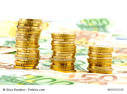  Stapel Geldscheine und Münzen als Symbol für Finanzen